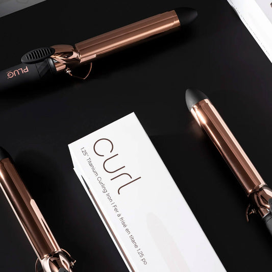 Plug By Must52 Curl Titanium Curling Iron — rose-gold titanium curling iron with its Curl carton on a black surface