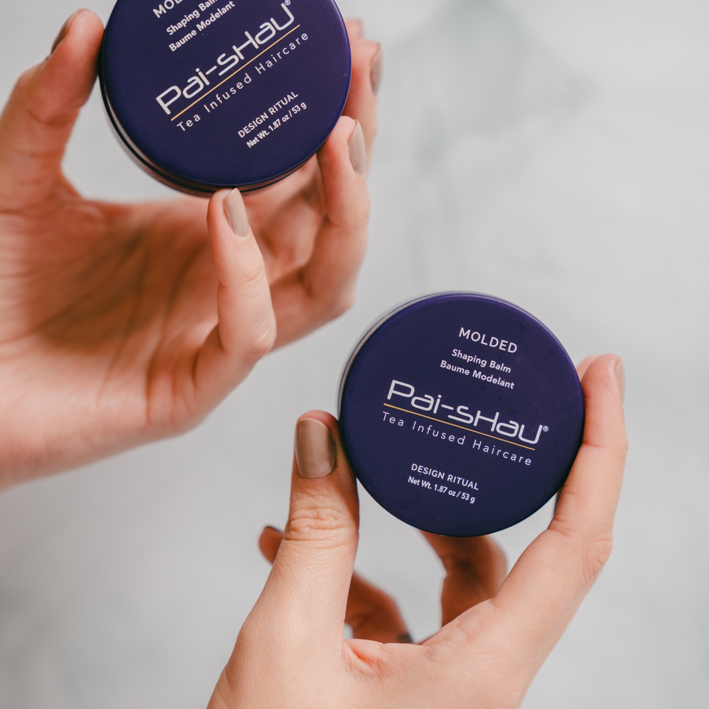 Pai-Shau Shaping Balm — Molded shaping balm jar held in two hands