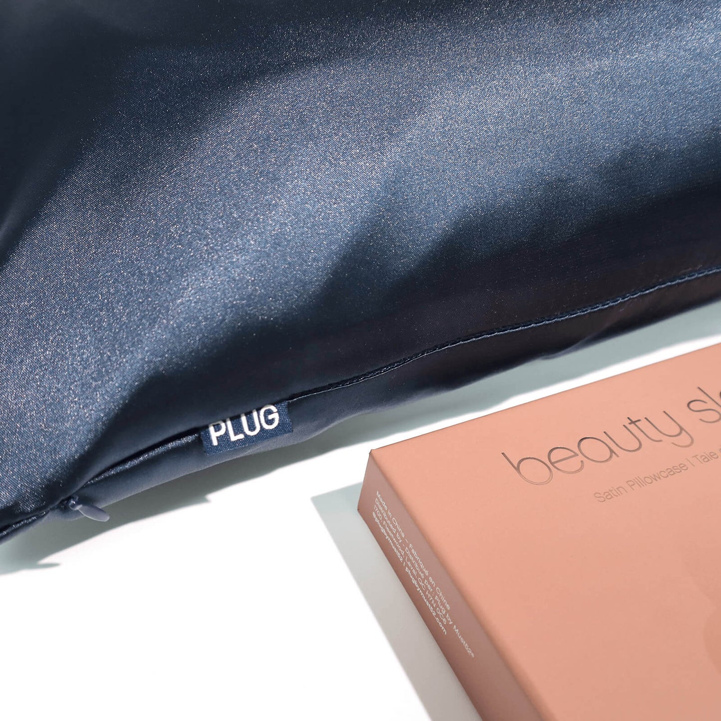 Plug By Must52 Satin Pillowcase — Midnight Blue satin pillowcase on a pillow beside its box, showing the sheen