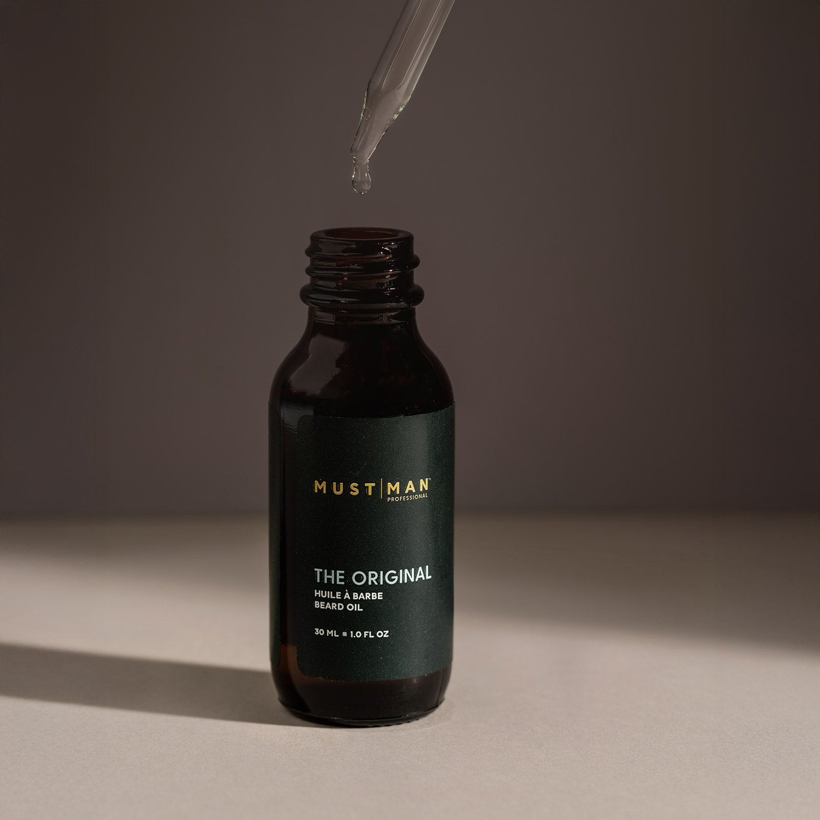 Must Man Professional The Original Beard Oil — 30 ml dropper bottle with the pipette raised above it, dark moody lifestyle shot