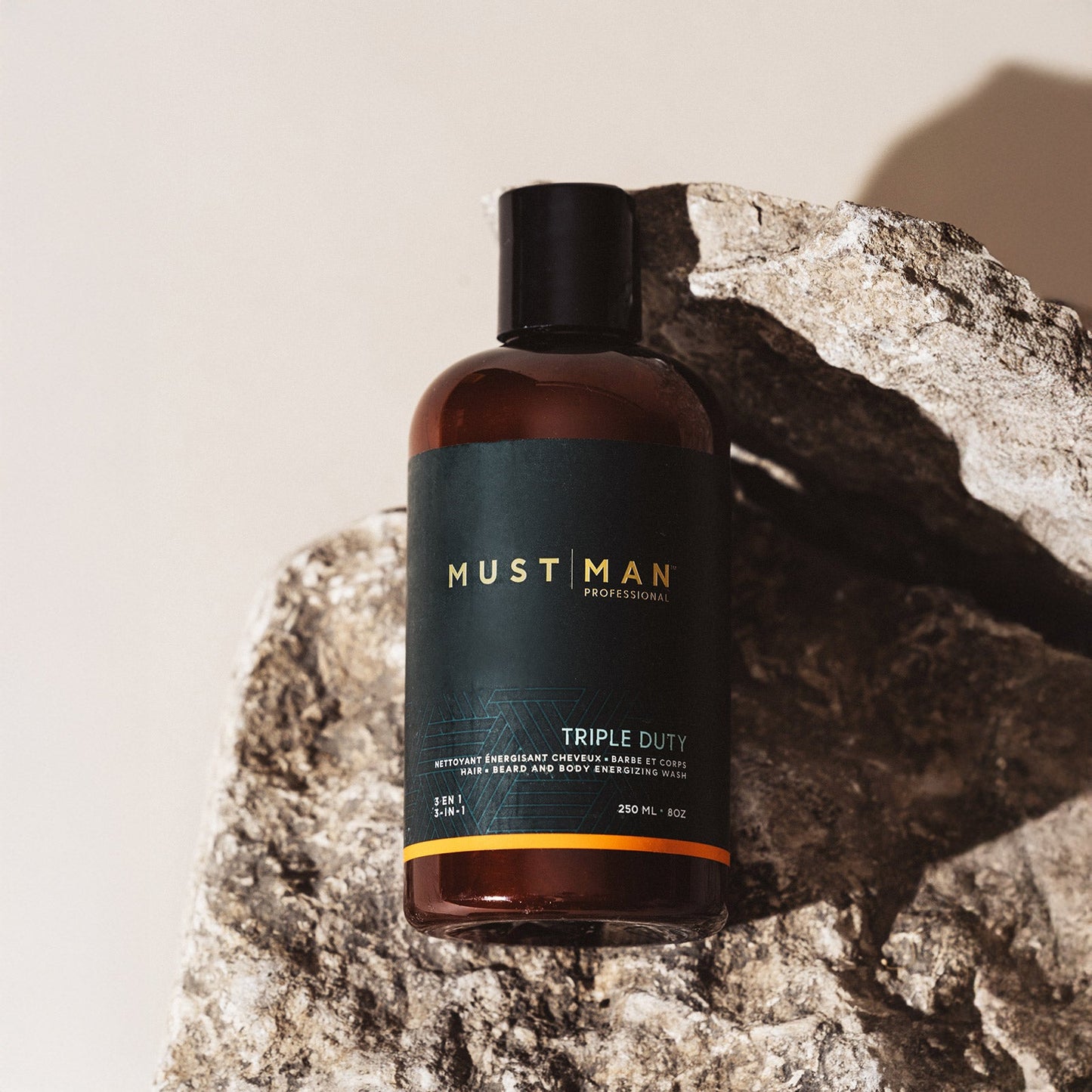 Must Man Professional Triple Duty Hair, Beard & Body Wash — 250 ml amber bottle propped on rock, lifestyle shot