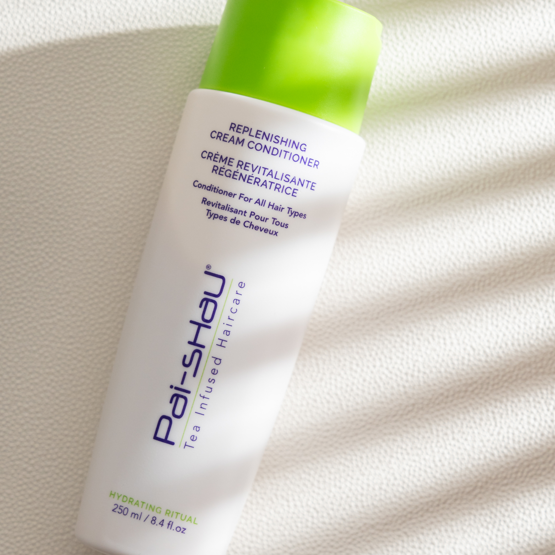 Pai-Shau - Replenishing Cream Conditioner — new-livery white 250 ml bottle angled against a ribbed white surface