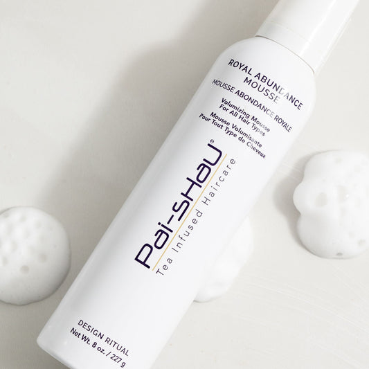 Pai-Shau Volumizing Mousse — current-livery white 227 g mousse can lying beside textured spheres