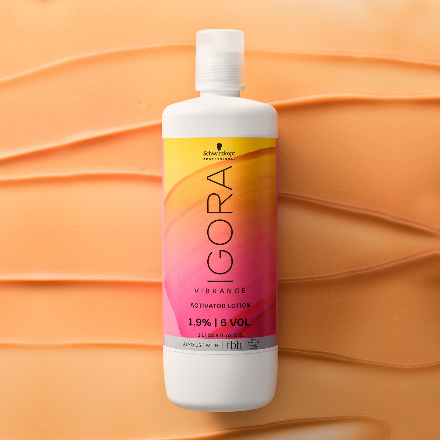 Schwarzkopf IGORA Vibrance Activator Lotion — current-livery activator lotion bottle laid on a swept colour texture