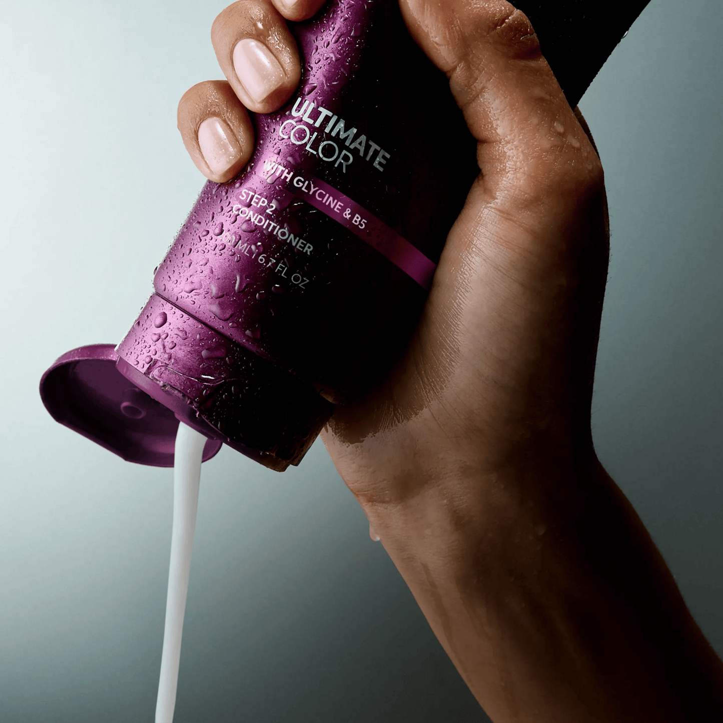 Wella Professionals Ultimate Color — Image of model's hand squeezing a bottle of the Ultimate Color conditoner. Text overlay reads " Smooth, creamy texture for porous strands".
