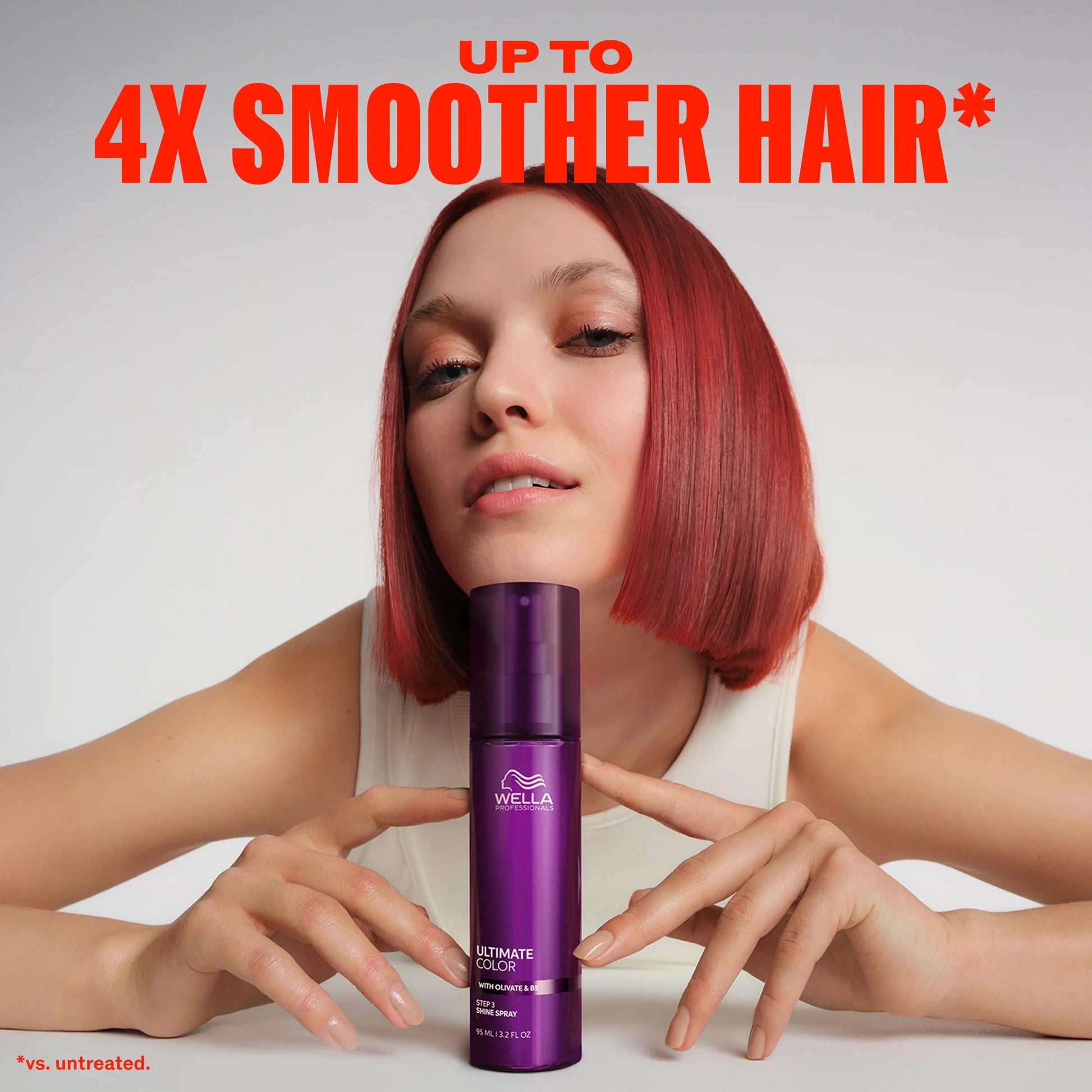 Wella Professionals Ultimate Color — Model with short, red hair leaning their chin against a bottle of Ultimate Color shine spray. Text overlay reads "Up to 4x smoother hair* *vs.untreated".